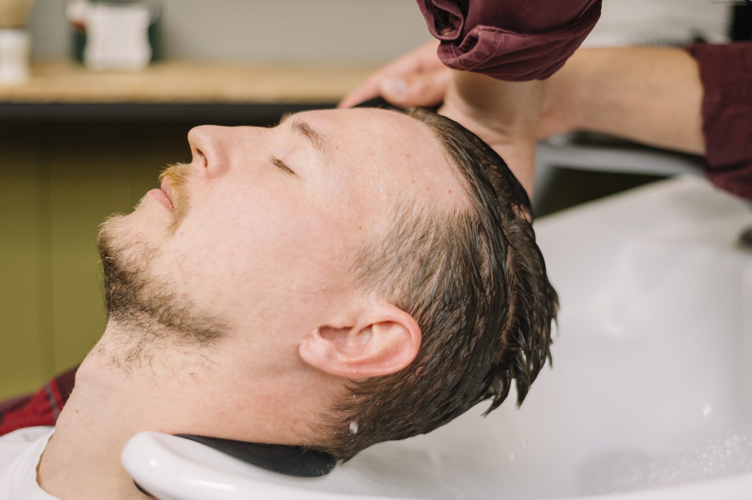 A client relaxing while receiving a professional hair wash at a barbershop in Larnaca, using premium barber hair care products.