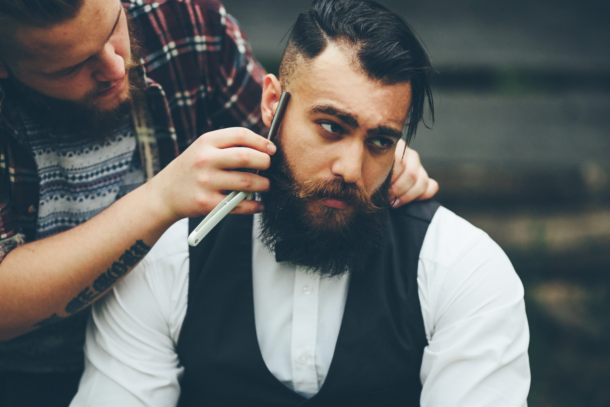 A bearded man getting a traditional straight razor shave by a barber in Cyprus.