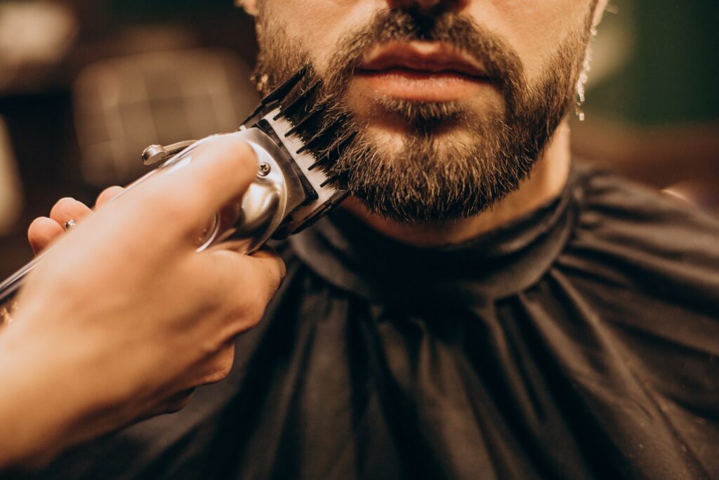 A close-up of a barber trimming a man's beard with electric clippers in a Cyprus barbershop.