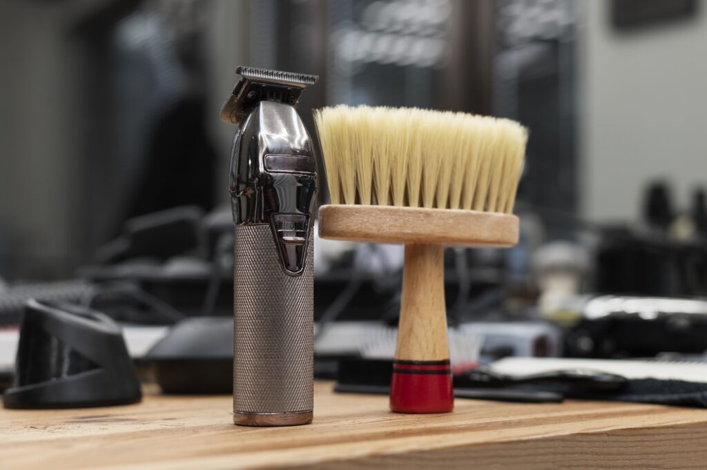 A professional hair clipper and barber brush on a wooden counter in a barbershop.