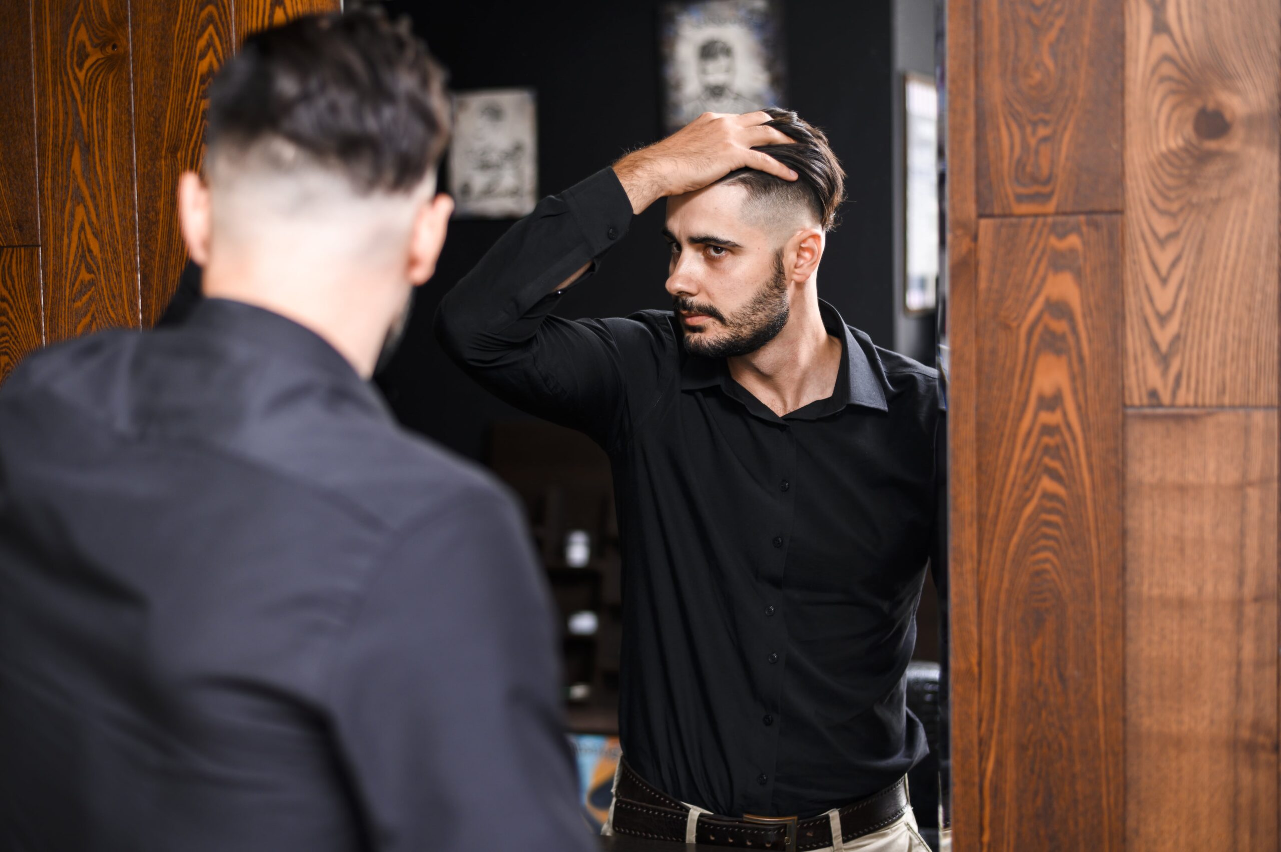 Man checking his modern fade haircut in the mirror, showcasing one of the best hairstyles for men.