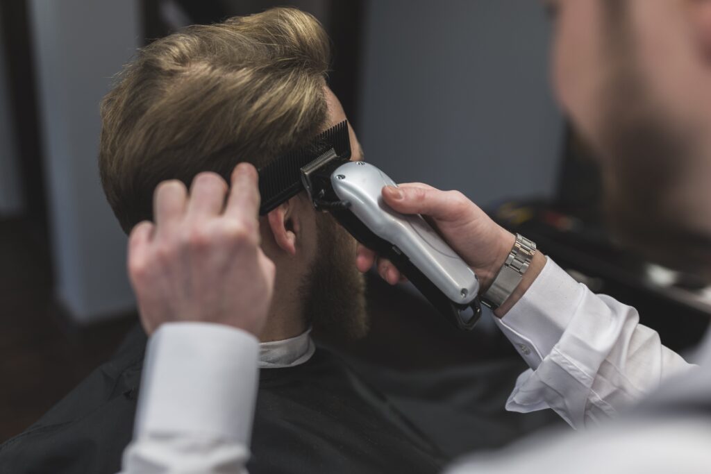 Barber trimming a man's hair with clippers, creating one of the best hairstyles for men.